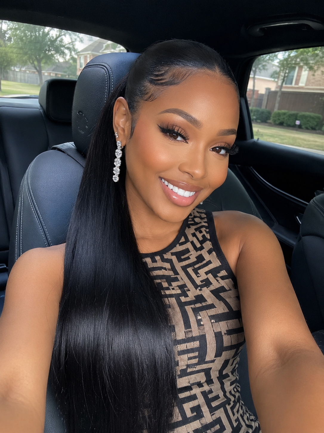 Woman sitting in a car wearing a patterned dress and long black ponytails.